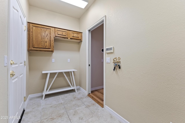 laundry area with light tile patterned flooring and baseboards