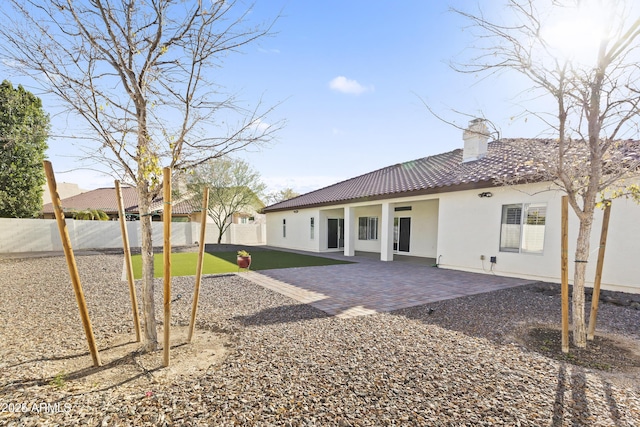 rear view of house featuring a chimney, a patio area, a fenced backyard, and stucco siding