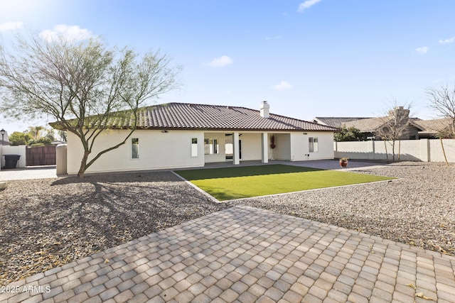 rear view of property featuring a tile roof, a chimney, fence, a patio area, and stucco siding