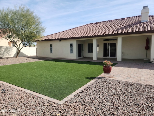 rear view of property featuring a tile roof, a patio area, fence, and stucco siding