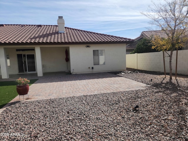 back of property featuring a patio, a chimney, and a fenced backyard