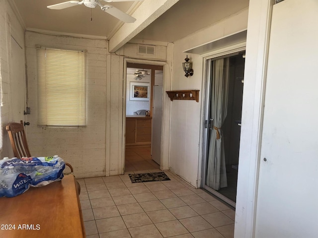 corridor with brick wall, crown molding, and light tile patterned flooring