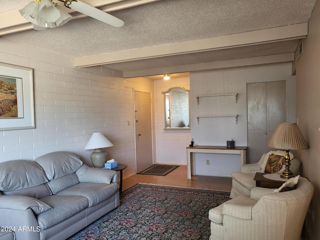 living room with ceiling fan, brick wall, dark hardwood / wood-style floors, and beamed ceiling