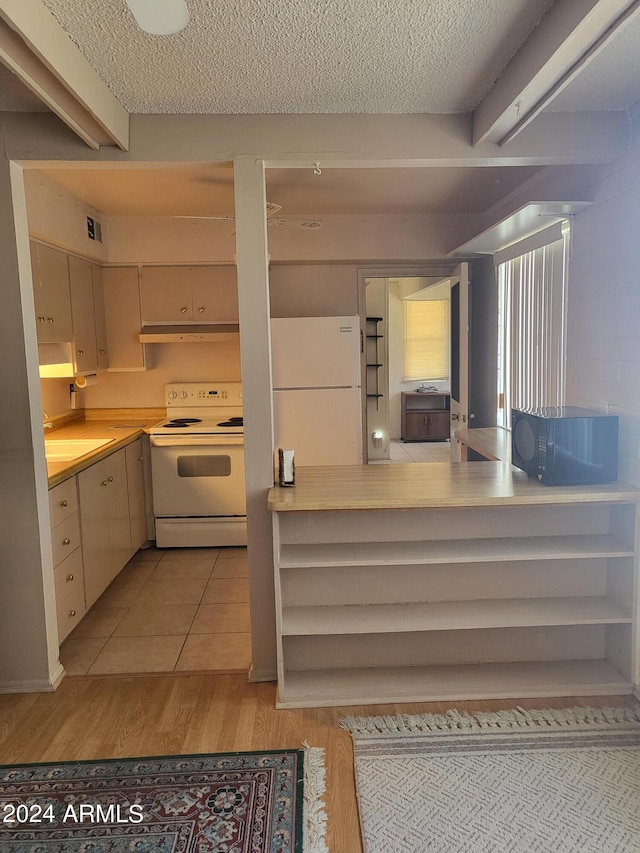 kitchen with cream cabinets, white appliances, a textured ceiling, range hood, and sink