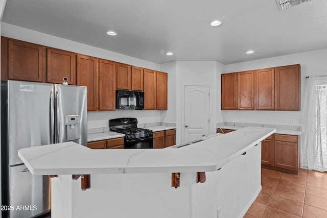 kitchen featuring black appliances, sink, a kitchen breakfast bar, and a kitchen island