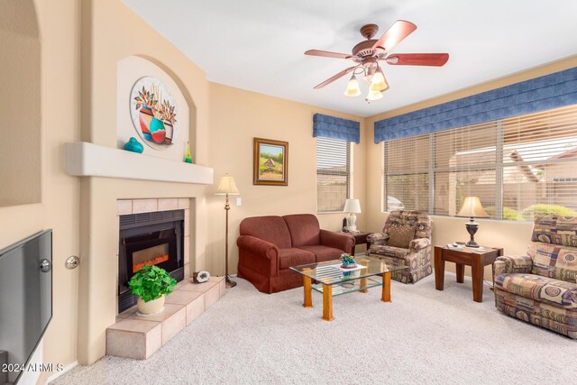 carpeted living room featuring ceiling fan and a tile fireplace