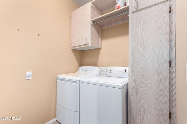 clothes washing area with cabinets and washer and clothes dryer