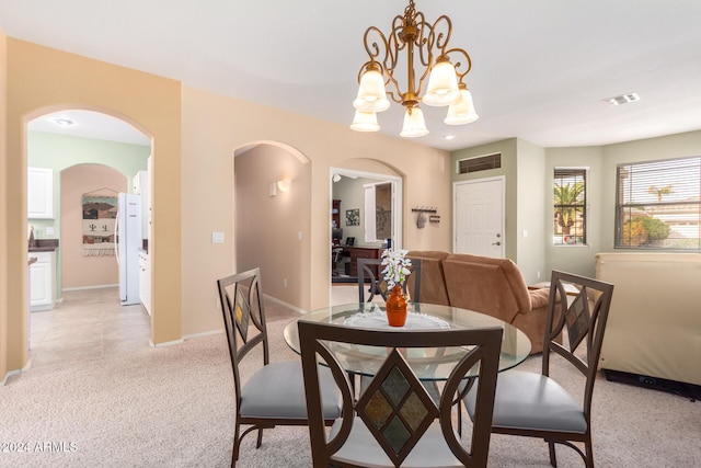 dining area featuring light carpet and a notable chandelier