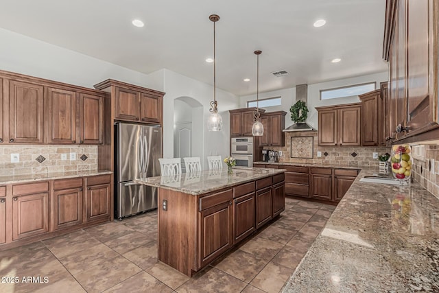 kitchen with stainless steel appliances, arched walkways, a kitchen island, decorative backsplash, and recessed lighting