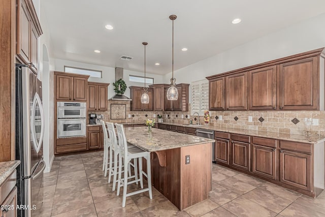 kitchen with appliances with stainless steel finishes, a sink, tasteful backsplash, a center island, and a breakfast bar area