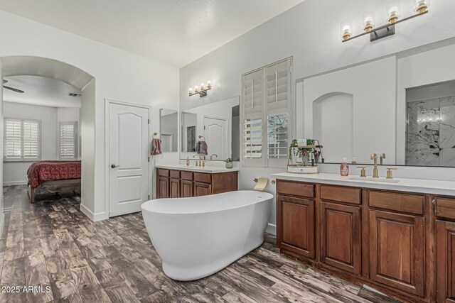 ensuite bathroom with a freestanding tub, two vanities, and wood finished floors