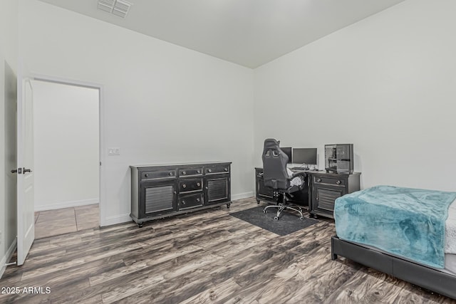bedroom with a desk, wood finished floors, and baseboards