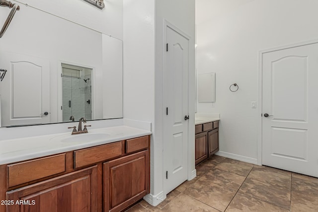 bathroom featuring a stall shower, two vanities, and baseboards