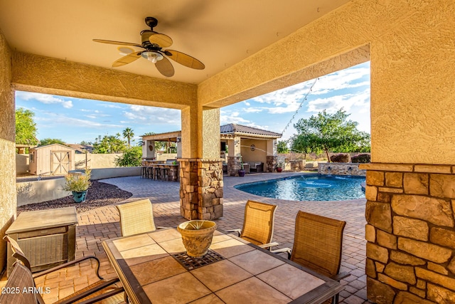view of swimming pool with outdoor dining area, a patio, an outbuilding, a storage unit, and ceiling fan