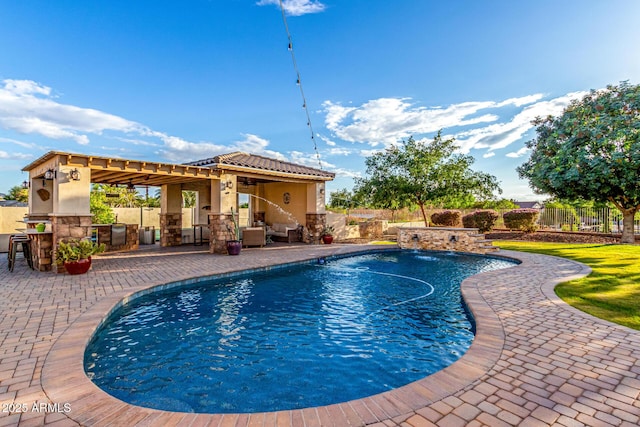 view of pool featuring fence, a patio, and an outdoor kitchen