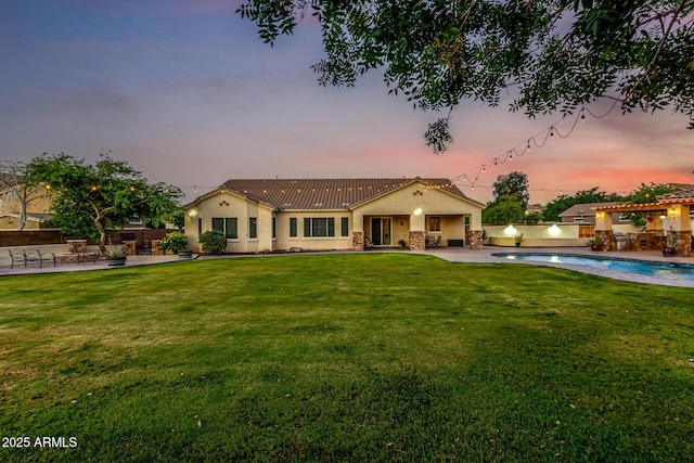 rear view of property with stucco siding, a patio area, a tile roof, and stone siding