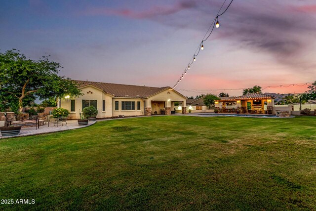 rear view of house featuring a patio area, a tile roof, stucco siding, a yard, and a pool