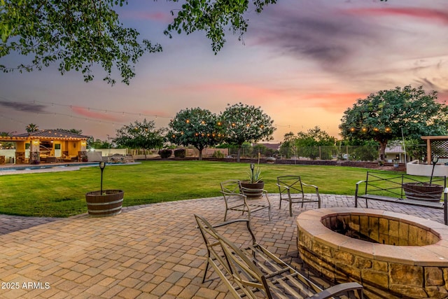 patio terrace at dusk with an outdoor fire pit and a swimming pool