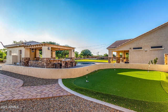view of yard featuring an area to practice putting, a bar, a patio, and a gazebo