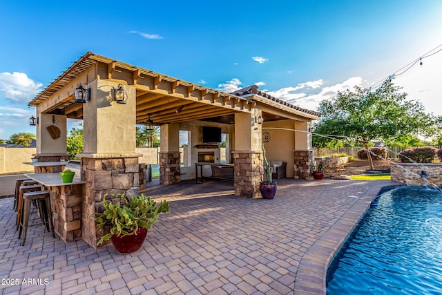 view of pool with a gazebo, a fireplace, a patio, and fence