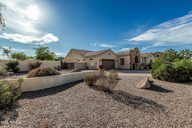 mediterranean / spanish-style house with a garage, fence, stucco siding, a tile roof, and driveway