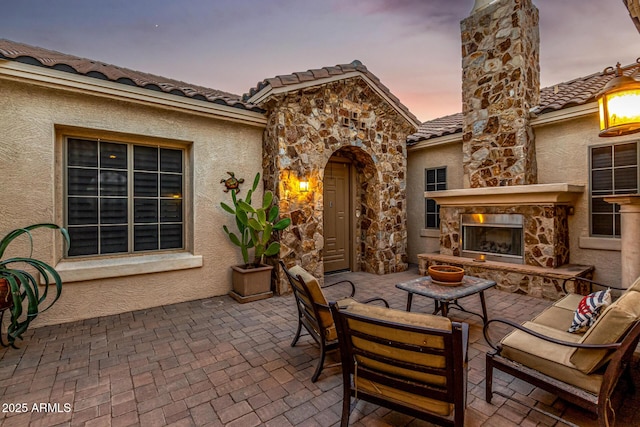 patio terrace at dusk featuring an outdoor living space with a fireplace