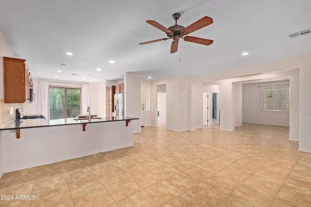 interior space featuring ceiling fan, sink, light tile flooring, backsplash, and stainless steel fridge with ice dispenser