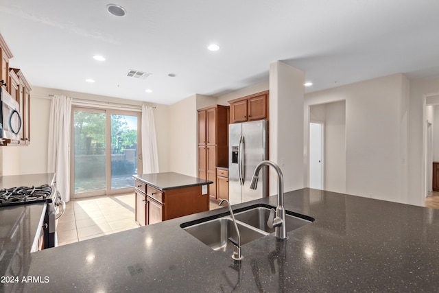 kitchen featuring a kitchen island, sink, stainless steel appliances, and dark stone counters