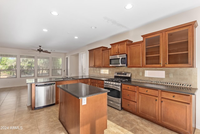 kitchen with appliances with stainless steel finishes, ceiling fan, sink, a center island, and light tile floors