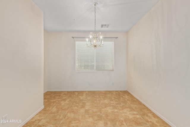 empty room with light tile flooring and an inviting chandelier