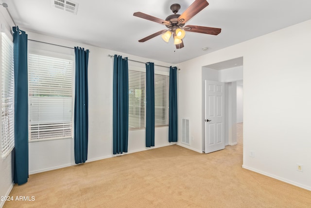 spare room with plenty of natural light, light carpet, and ceiling fan