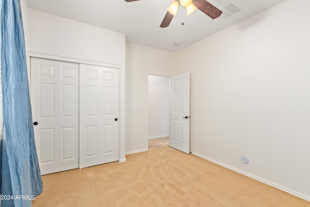 unfurnished bedroom featuring light carpet, a closet, and ceiling fan