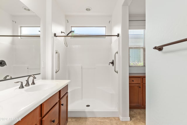 bathroom featuring a shower, plenty of natural light, large vanity, and tile flooring