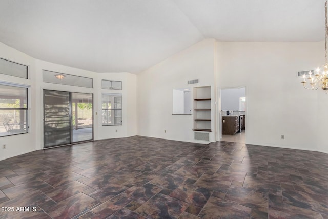 unfurnished living room featuring plenty of natural light, high vaulted ceiling, and a chandelier