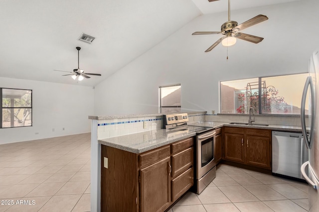 kitchen featuring kitchen peninsula, appliances with stainless steel finishes, light stone counters, sink, and light tile patterned floors