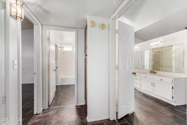 bathroom with vanity, washtub / shower combination, and a textured ceiling