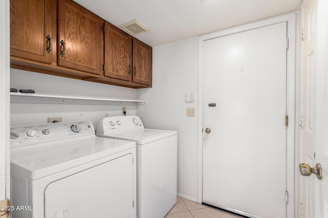 laundry area featuring cabinets, light tile patterned floors, and washing machine and clothes dryer