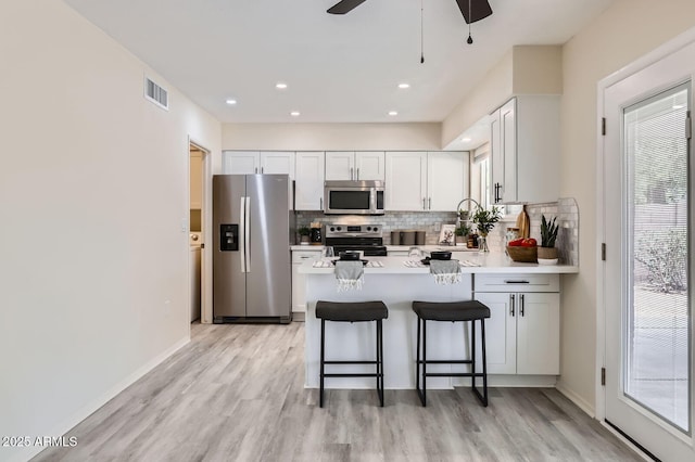 828 E Le Marche Ave, Phoenix, AZ 85022 - kitchen featuring appliances with stainless steel finishes, decorative backsplash, light wood-style floors, a peninsula, and light countertops