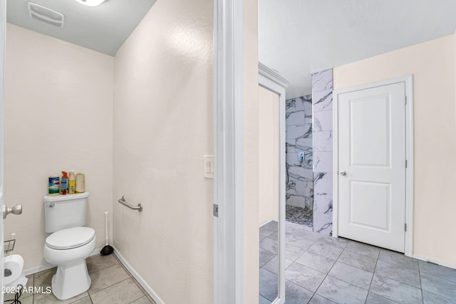 bathroom featuring tile patterned flooring, a shower, and toilet