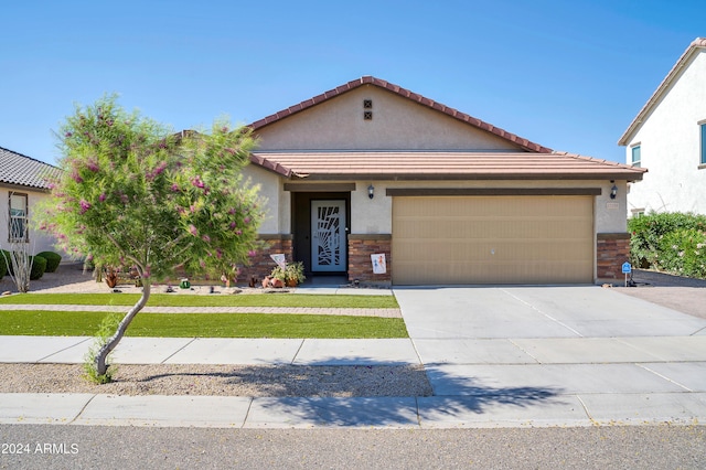 view of front of property featuring an attached garage, stucco siding, concrete driveway, stone siding, and a tiled roof