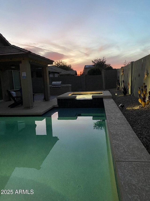 pool at dusk with an in ground hot tub