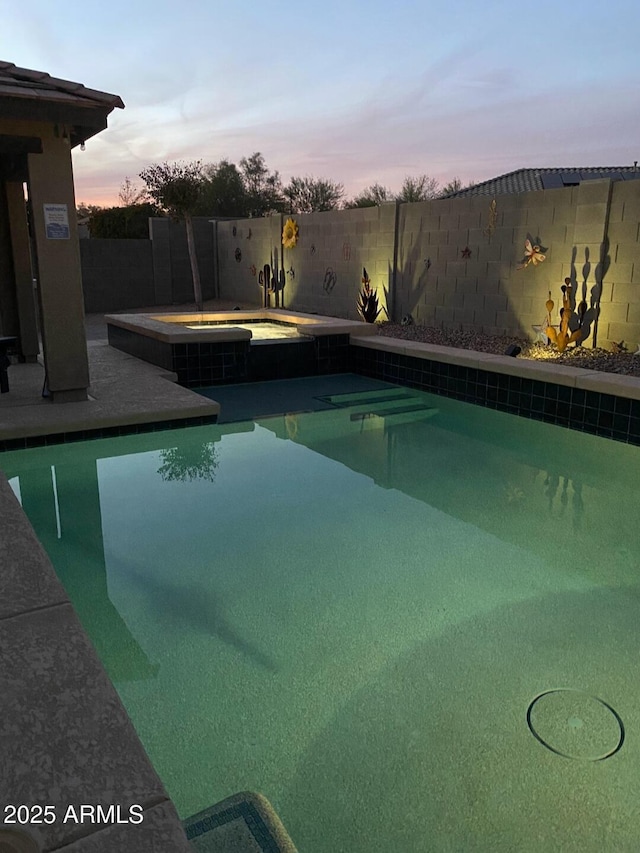 pool at dusk featuring an in ground hot tub