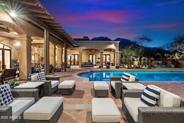 pool at dusk featuring ceiling fan, an outdoor living space, a fenced in pool, and a patio