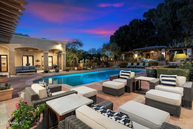 pool at dusk featuring a ceiling fan, outdoor lounge area, an outdoor pool, a pergola, and a patio