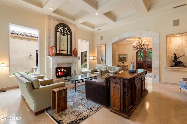 living room with arched walkways, beamed ceiling, a chandelier, and a high ceiling