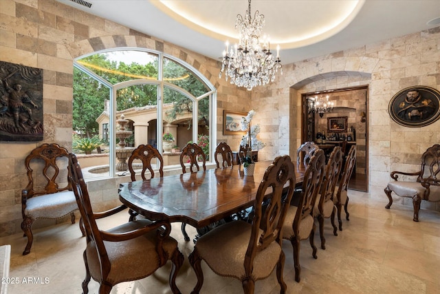 dining area featuring an inviting chandelier, arched walkways, and a tray ceiling