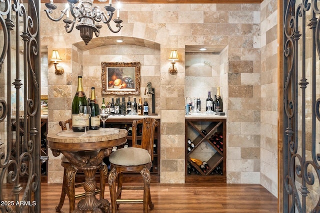 wine cellar featuring an inviting chandelier, a dry bar, and wood finished floors