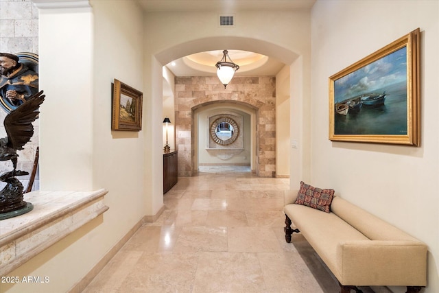 corridor featuring visible vents, arched walkways, and baseboards