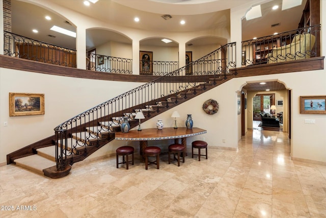 staircase featuring visible vents, a high ceiling, recessed lighting, and baseboards