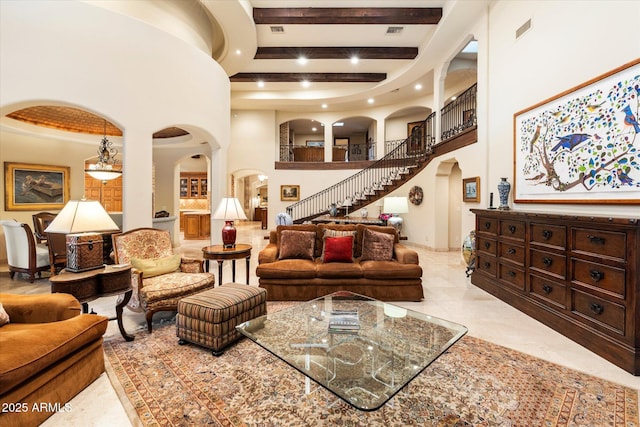 living area with stairway, beam ceiling, recessed lighting, a high ceiling, and arched walkways